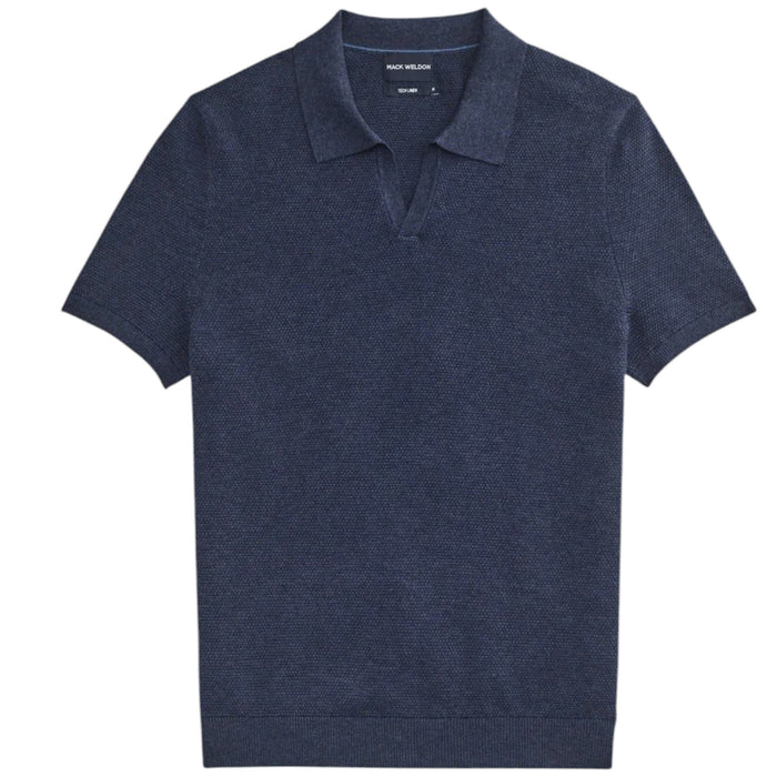 A close-up of a person’s arm and torso wearing the MACK WELDON Tech Linen Johnny Collar Polo Sweater in Navy Heather, paired with light gray pants featuring a buttoned pocket.