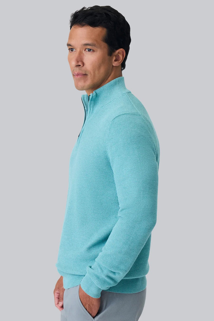 A man faces away from the camera, wearing the MACK WELDON Tech Linen Quarter Zip in Deep Lagoon Heather with COOLMAX® technology and gray pants. The background is plain light gray.