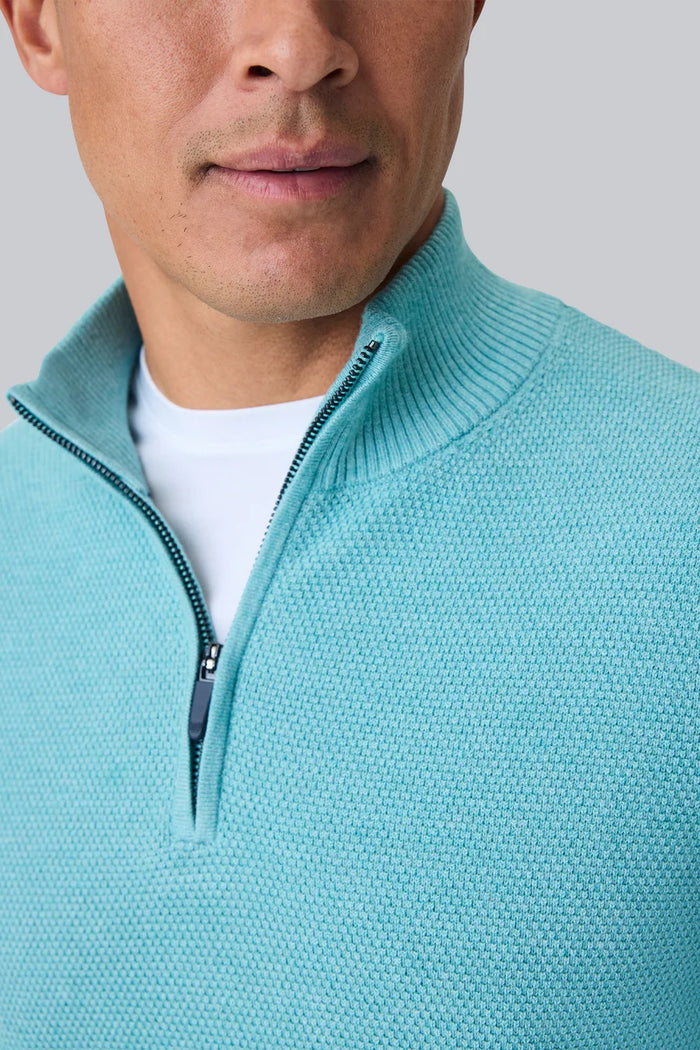 A man faces away from the camera, wearing the MACK WELDON Tech Linen Quarter Zip in Deep Lagoon Heather with COOLMAX® technology and gray pants. The background is plain light gray.
