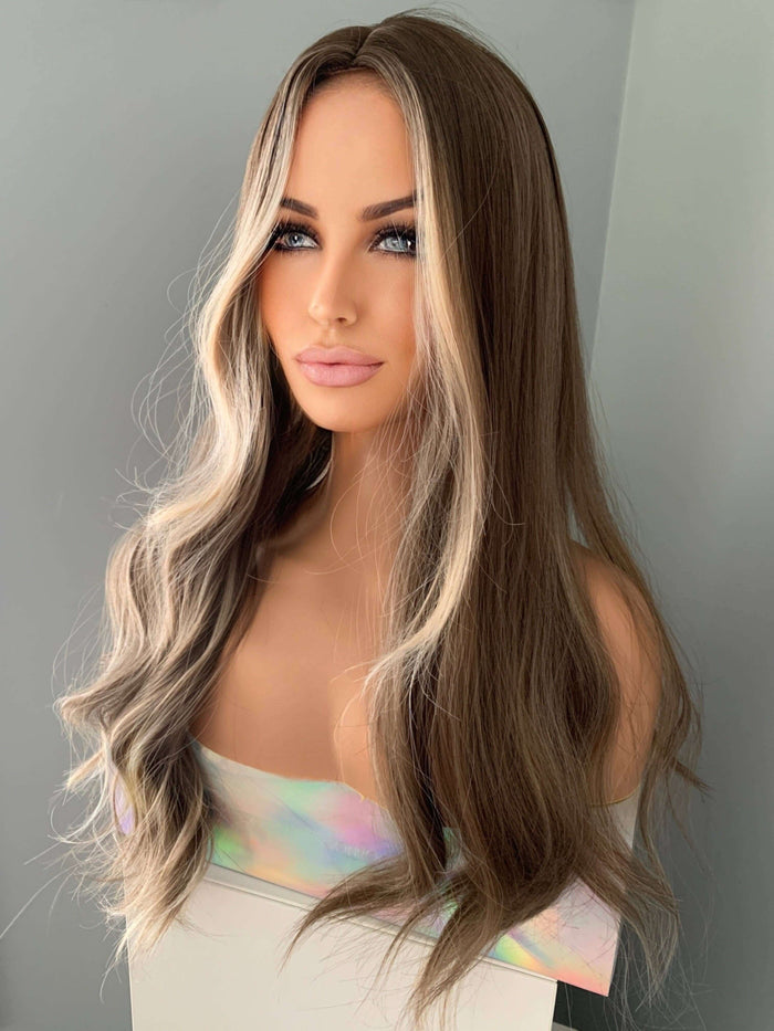 Person with long, wavy hair styled in a way that highlights the color transition from brown to blonde.