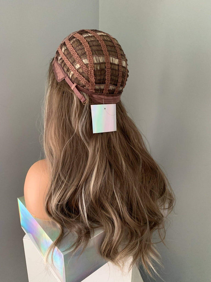 Mannequin head with long wavy hair wearing a patterned cap against a plain background