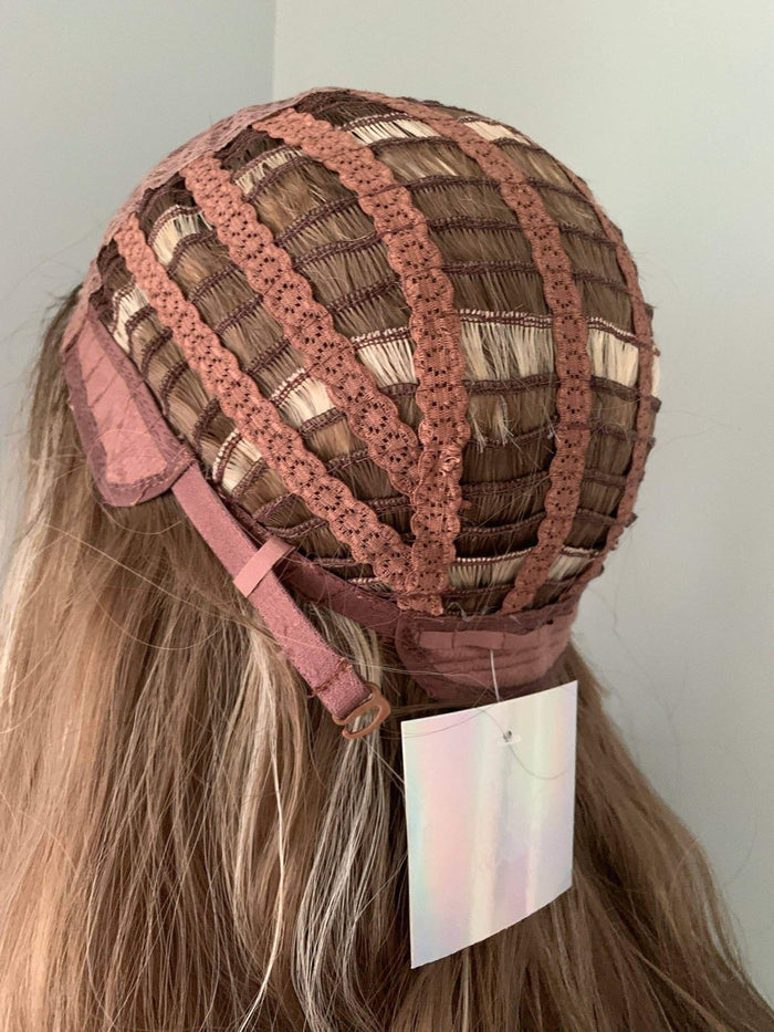 Brown hair extensions on a mannequin head with a pink cap, against a plain background.