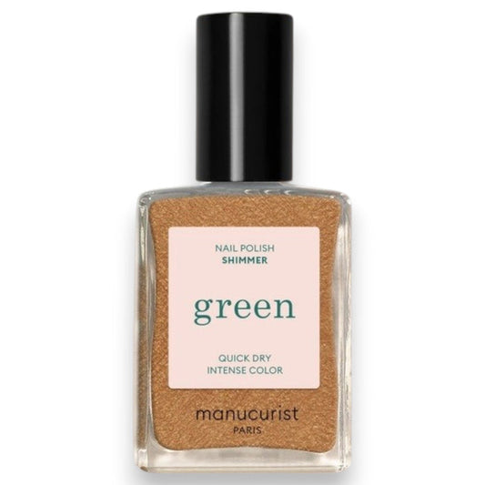 A hand adorned with metallic gold vegan nail polish holds a bottle of MANUCURIST - GREEN™ NAIL POLISH IN SHIMMER by MANUCURIST INC, set against a textured, light-filled background.