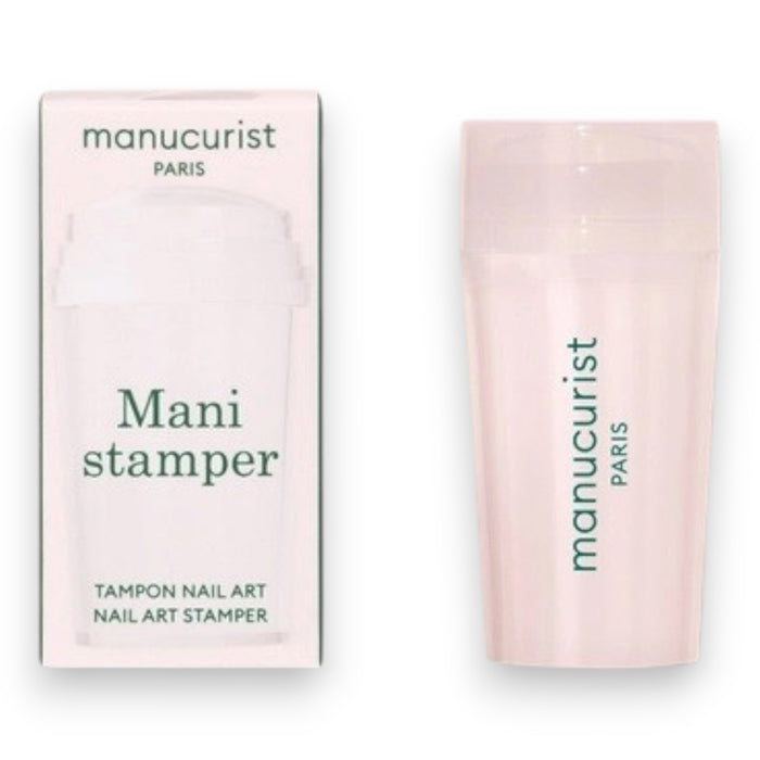 A hand with a light pink French manicure rests beside the MANUCURIST - MANI STAMPER by MANUCURIST INC on a pale background.