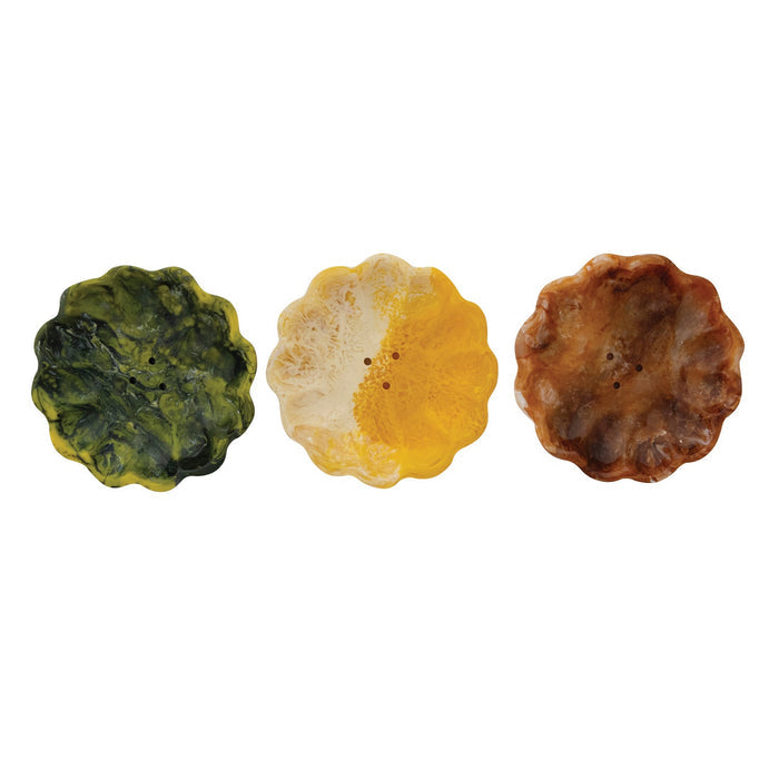 Three CREATIVE COOP MARBLED RESIN FLOWER-SHAPED SOAP DISHES in green, brown, and yellow are displayed side by side on a plain white background. Each decorative dish features scalloped edges and a unique marbled pattern.