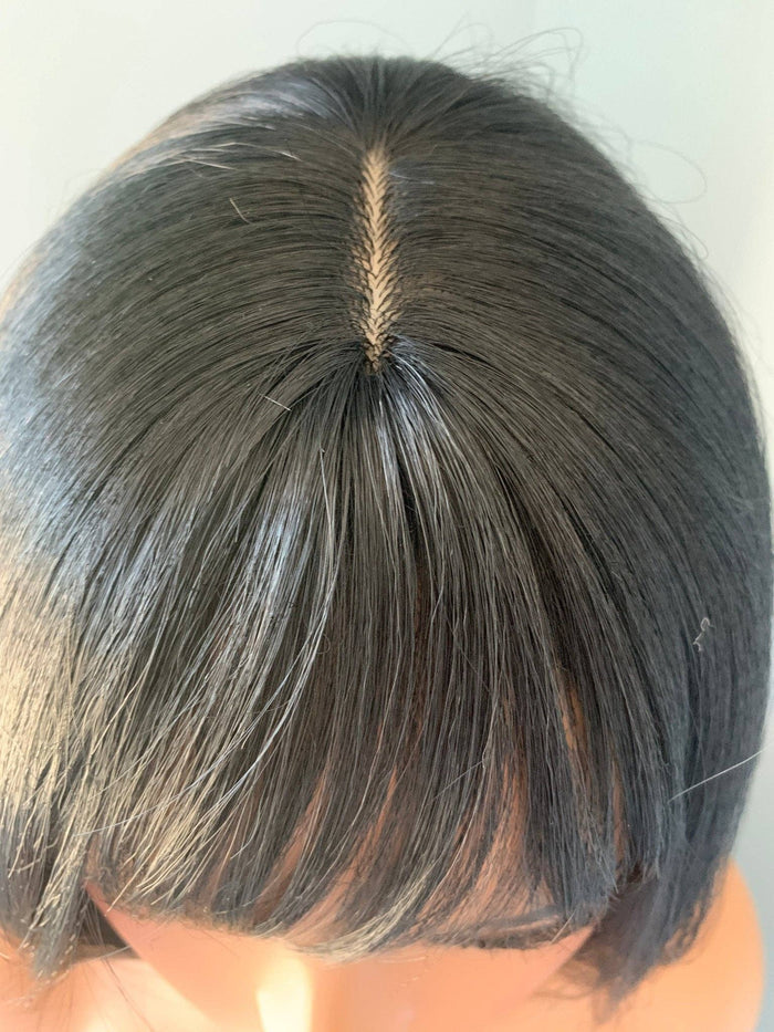 Close-up of a person's head with a short haircut and visible part line.