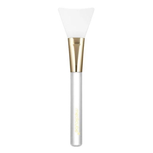 The MEDICUBE - JELLY BRUSH MASK APPLICATION TOOL by KOSMIC KBEAUTY SKINCARE is a hygienic mask applicator designed with a clear handle, gold ferrule, and a flexible, flat white silicone tip—making it the perfect tool for smooth and mess-free skincare routines.