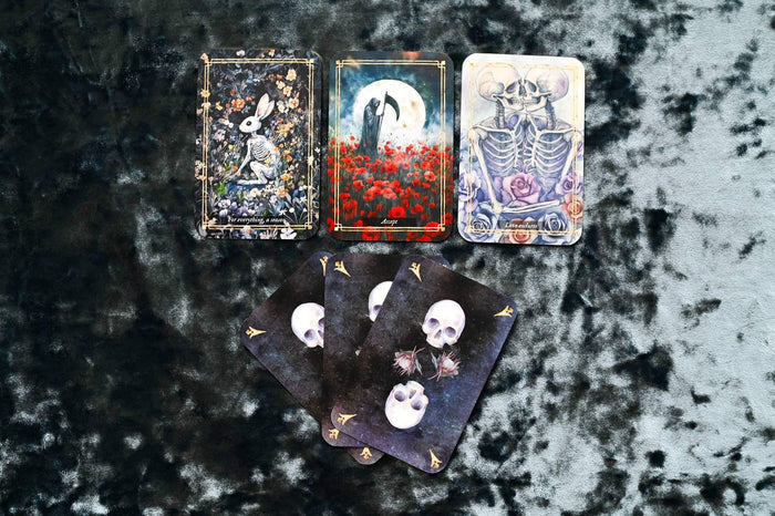 Memento Mori Cards displayed on dark fabric, featuring artwork symbolizing mindfulness and the appreciation of life.