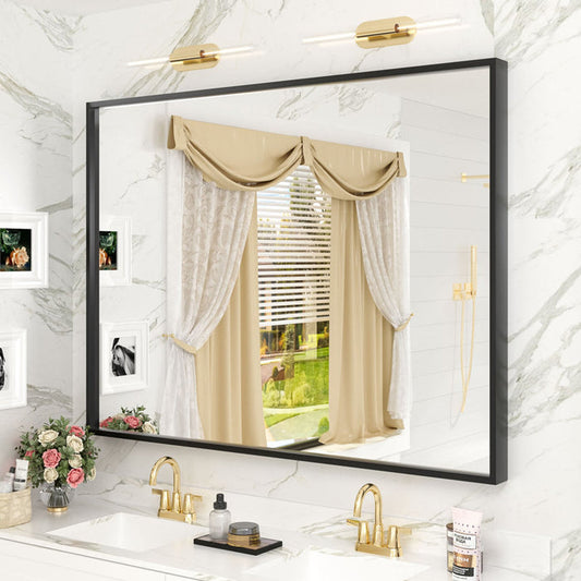 Bathroom mirror with black frame reflecting a window with beige curtains.