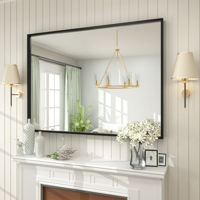 Decorative mirror on a wall with a chandelier and wall lamps in a home interior.