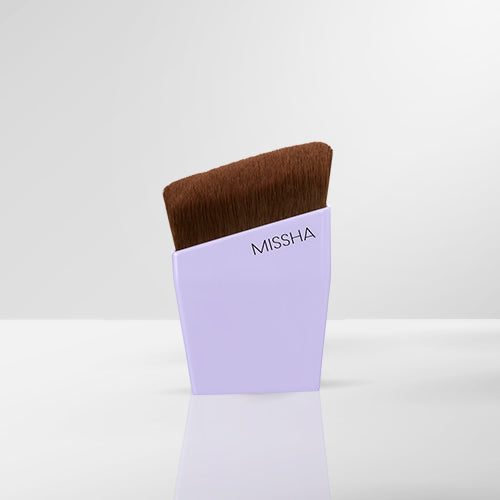 A MISSHA layering fit brush with brown bristles, partially inserted into a light purple holder with the brand name visible.