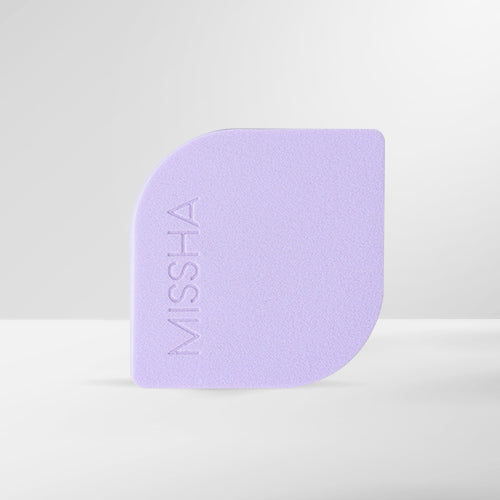 A purple, latex-free makeup puff with the MISSHA brand logo embossed on it.