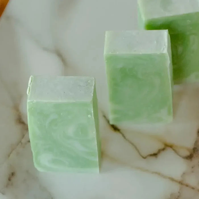Three green soap bars on a marble surface