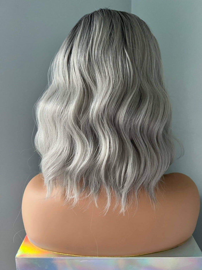 Silver wig on a mannequin head against a plain background