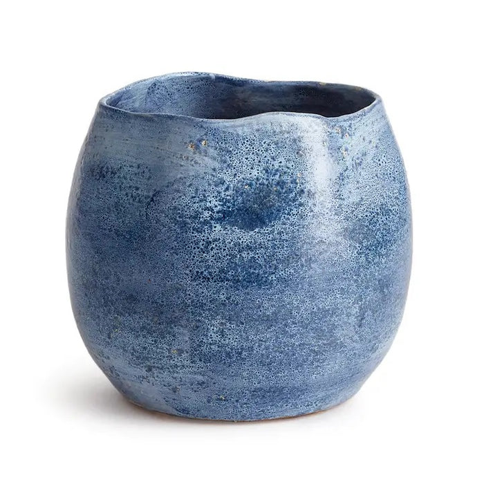 The NAPA HOME AND GARDEN - CASPIAN CACHEPOT is a round, blue ceramic vase with a glossy, mottled finish and speckled pattern—ideal for decorative use on any shelf or table.