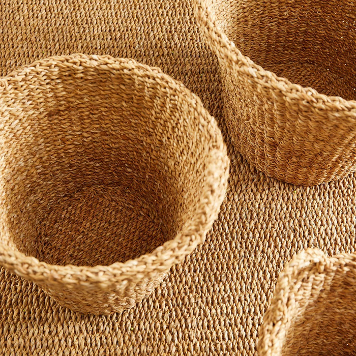The NAPA HOME AND GARDEN Seagrass Tapered Basket with Handles and Cuff, Large, is shown from above, highlighting its natural seagrass texture and expert craftsmanship on a matching surface.