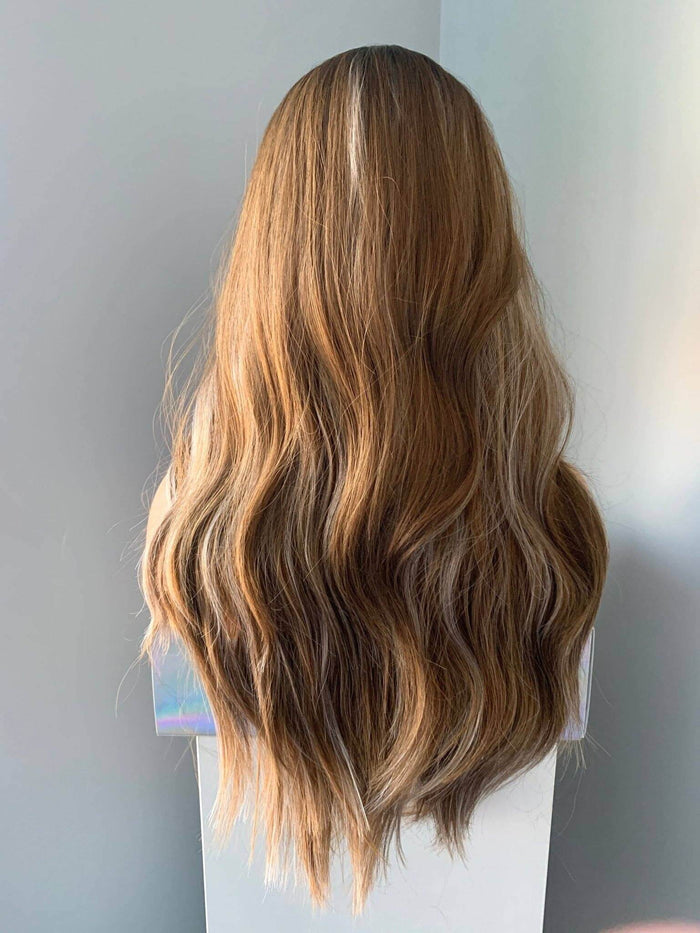 Brown wig on a mannequin head against a plain background