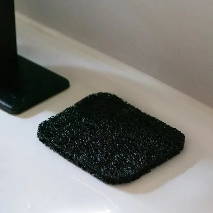 Black scrubber on a white surface with a neutral background