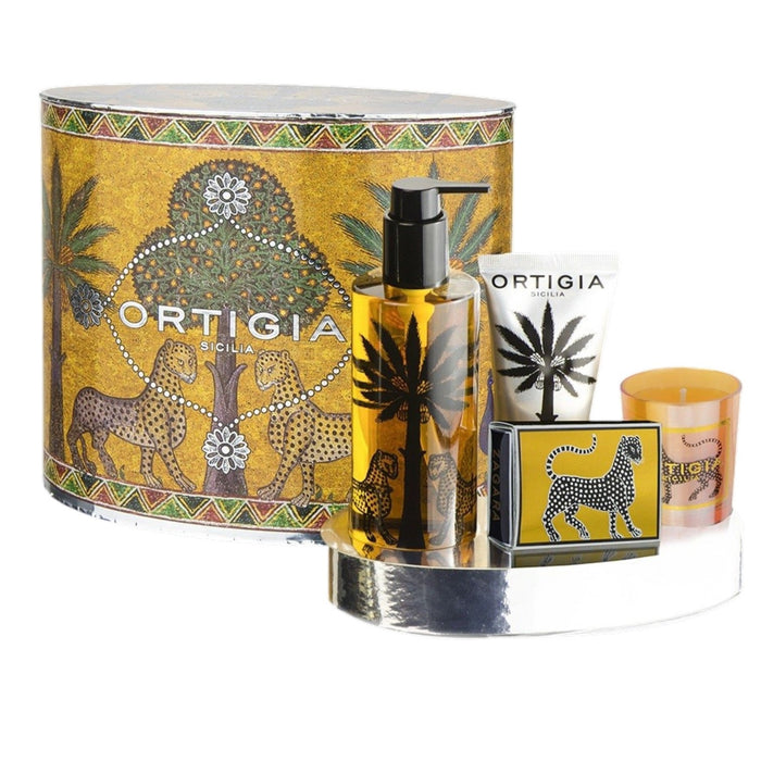 The ORTIGIA SICILIA - ZAGARA OVAL GIFT SET by ORTIGIA SICILIA features products infused with the refreshing scent of Sicilian orange blossoms, including a bottle, tube, soap, and candle. Each item is adorned with palm tree and leopard motifs and elegantly arranged on a shiny tray in front of an ornate yellow gift box.
