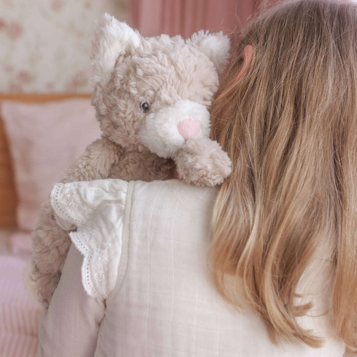 Child holding a teddy bear in a softly lit room with pink bedding.
