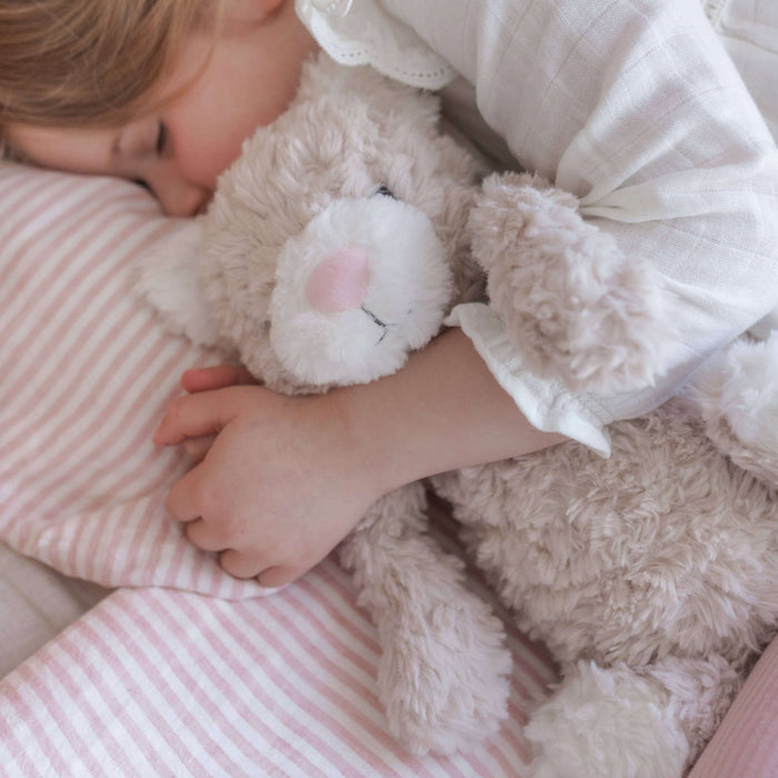 Child sleeping with a teddy bear on a pink striped bed