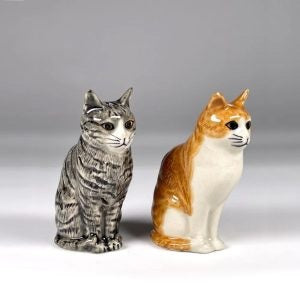 The QUAIL CERAMICS Squash & Patience Cat Salt & Pepper Shakers by QUAIL DESIGNS feature two hand-painted ceramic cat figurines sitting back to back—one in gray with black stripes and the other in orange with white patches. Each cat is looking away from the other, making this charming set a perfect gift for cat lovers.