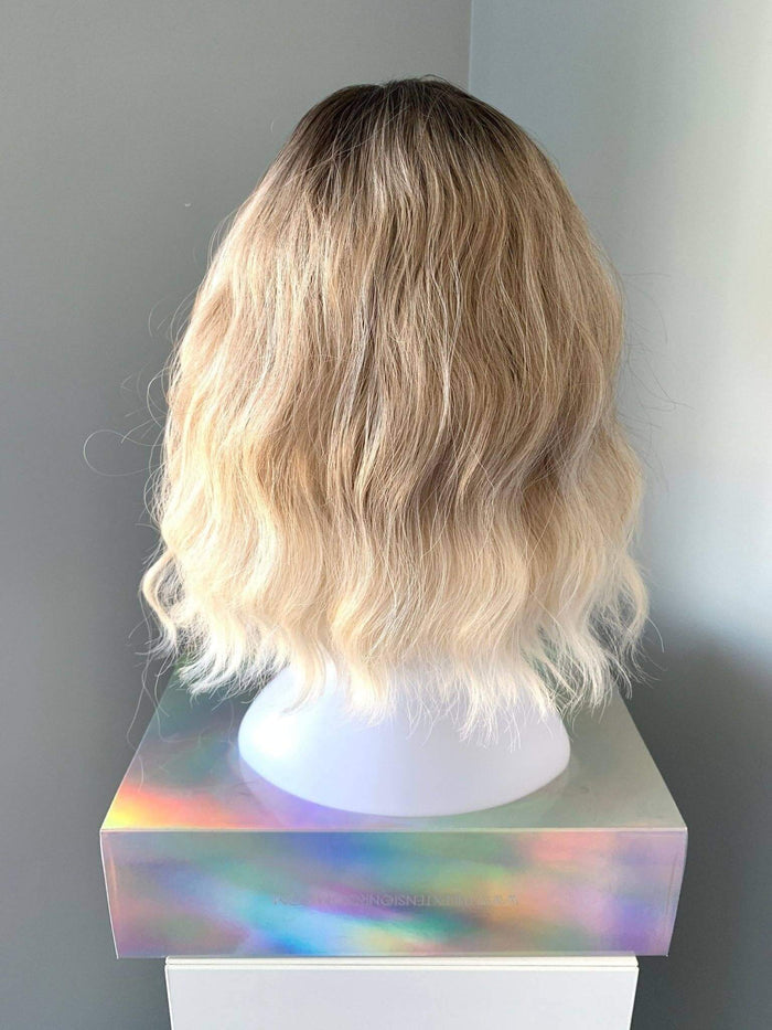 Back view of the Rebecca Short Blonde Body Wave Wig with Bangs showcasing soft waves and a natural look.