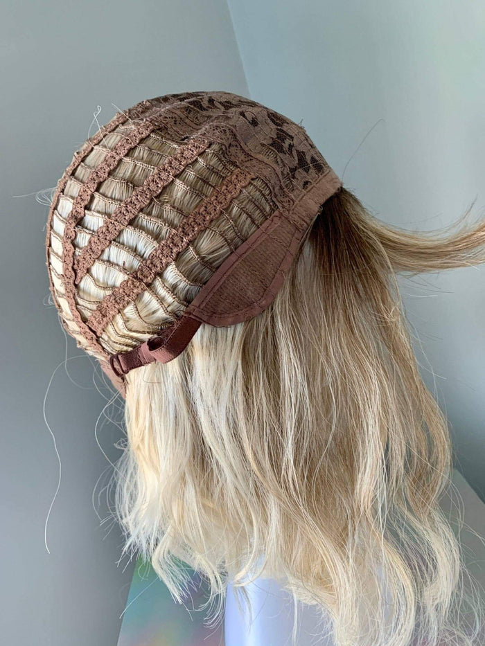 Close-up of the interior of a short blonde body wave wig with bangs showing the cap construction.