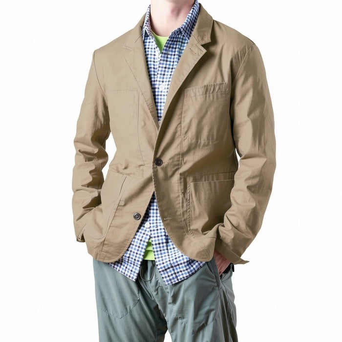 A person wears the RELWEN Flyweight Flex Blazer in British Khaki over a blue and white checkered shirt with green pants, standing hands-in-pockets against a white background. Face not visible.