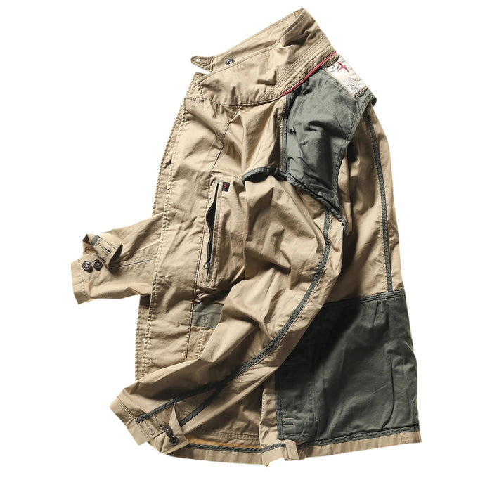 A person wears the RELWEN Flyweight Flex Blazer in British Khaki over a blue and white checkered shirt with green pants, standing hands-in-pockets against a white background. Face not visible.