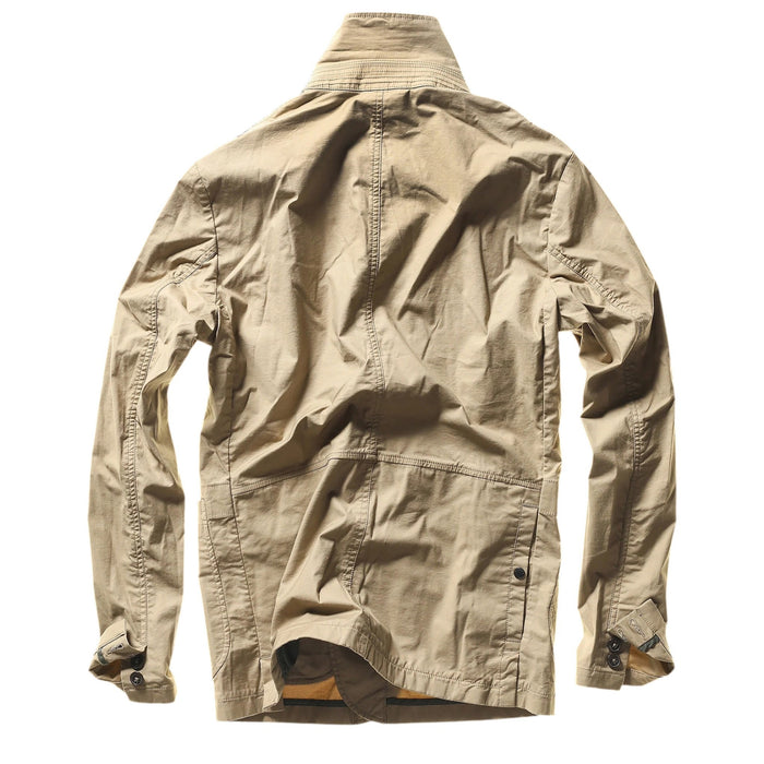 A person wears the RELWEN Flyweight Flex Blazer in British Khaki over a blue and white checkered shirt with green pants, standing hands-in-pockets against a white background. Face not visible.