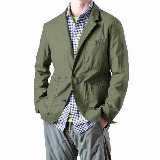 A person models the RELWEN Flyweight Flex Blazer in Burnt Olive over a blue and white checkered shirt with gray pants, hands in pockets, against a plain white background.