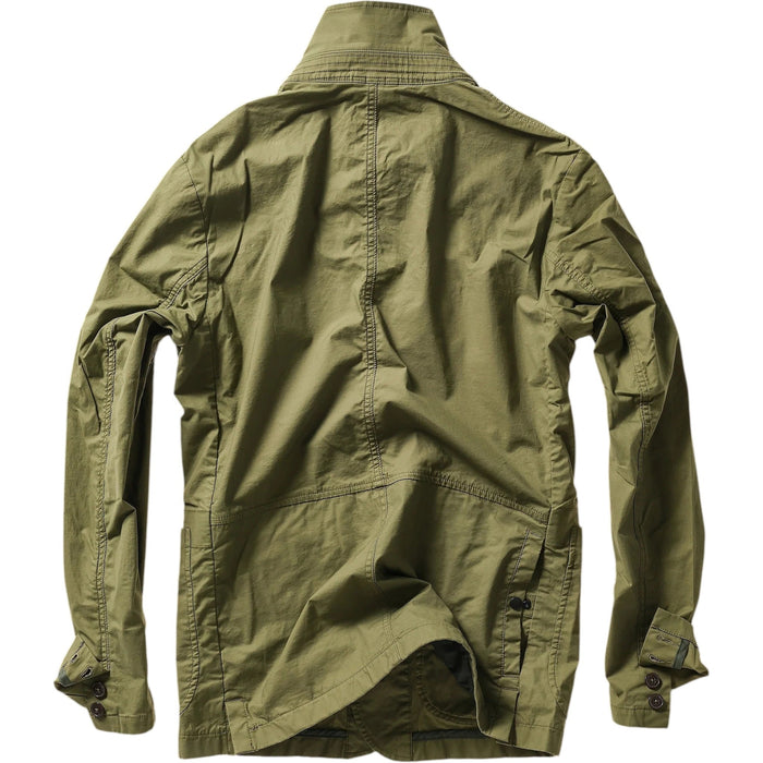 A person models the RELWEN Flyweight Flex Blazer in Burnt Olive over a blue and white checkered shirt with gray pants, hands in pockets, against a plain white background.