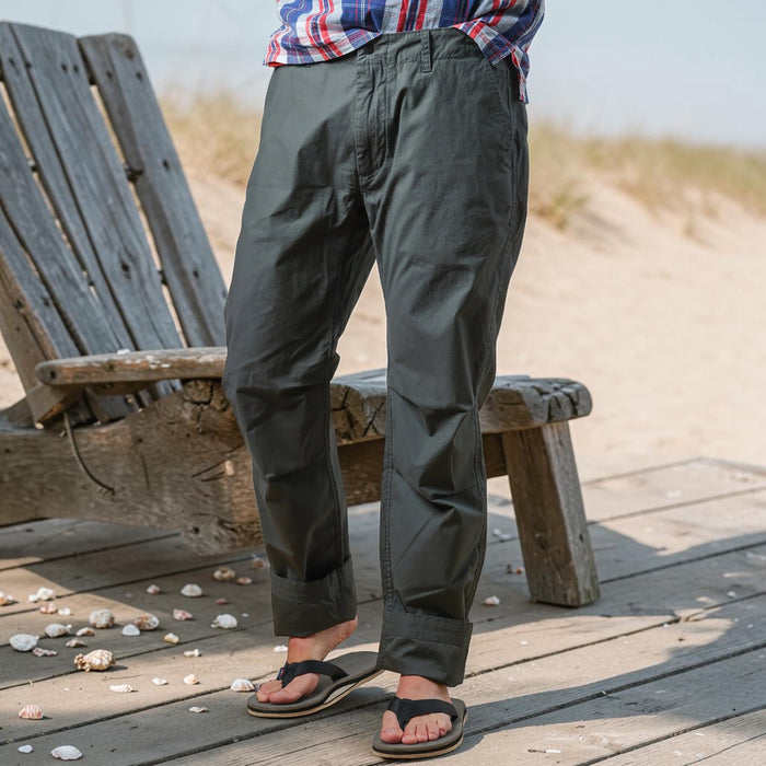 The RELWEN Flyweight Flex Chino in Charcoal, shown from the back with two buttoned pockets and subtle wrinkling, features a slim, straight-leg fit and lightweight stretch fabric for comfort. Pants are displayed flat on a white background.