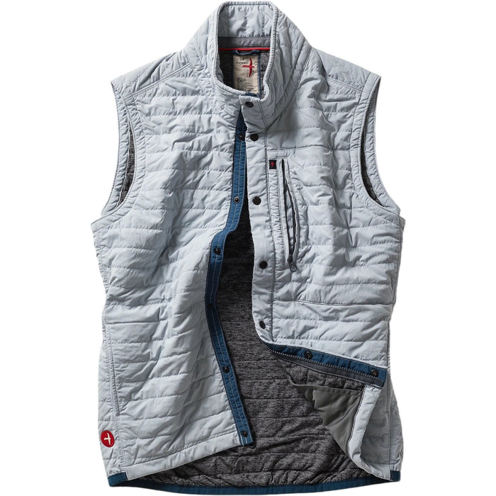 A person models the RELWEN - WINDZIP VEST IN GHOST GRAY over a gray sweater, plaid shirt, and dark blue jeans, standing with one hand in their pocket against a white background for extra layered warmth.