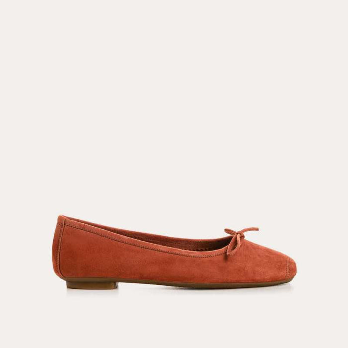 The REQINS - HARMONY Suede Ballerina Flat in Brique is shown in soft suede goatskin with a small bow on the toe, displayed side view against a plain white background.