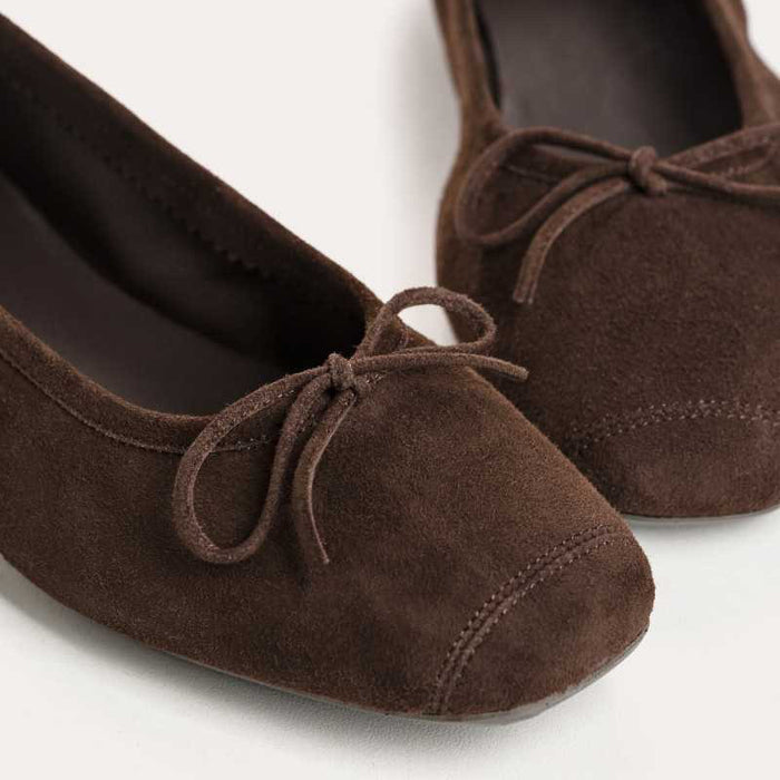 The REQINS Harmony suede ballerina flats in marron feature a rounded square toe and a small decorative bow on the front of each shoe.