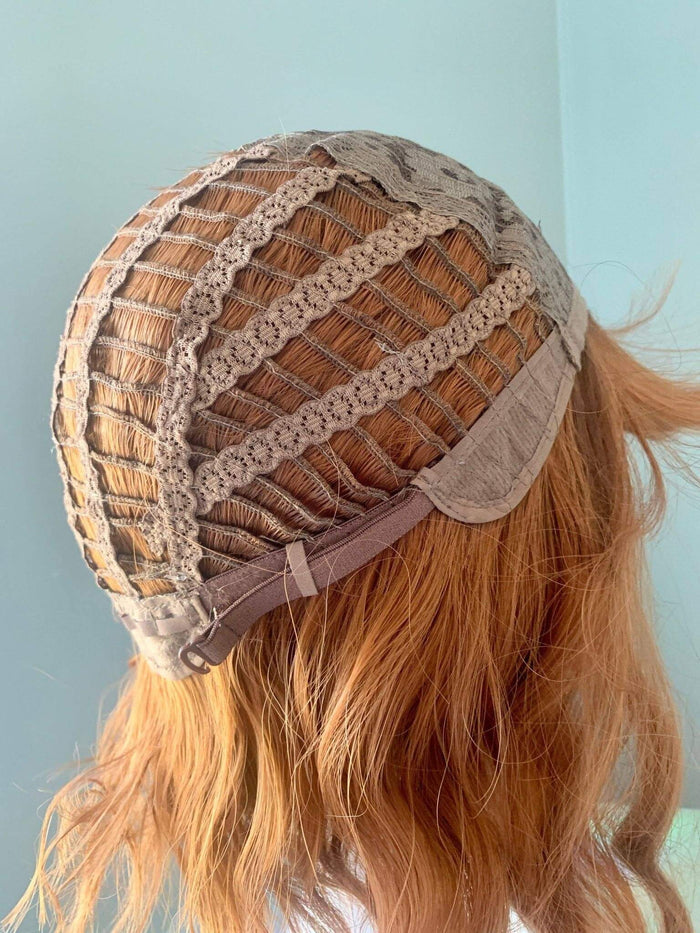 Wig with Bangs showing the interior cap construction of a short auburn body wave wig.