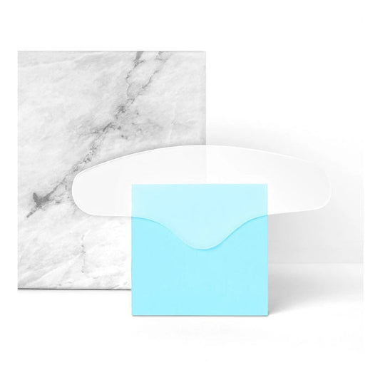 A blue envelope stands before a marble-patterned card with the SIO BEAUTY SIO BROWLIFT silicone wrinkle patch on top—a stylish, effective solution for forehead wrinkles—set against a white background.