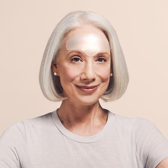 A blue envelope stands before a marble-patterned card with the SIO BEAUTY SIO BROWLIFT silicone wrinkle patch on top—a stylish, effective solution for forehead wrinkles—set against a white background.