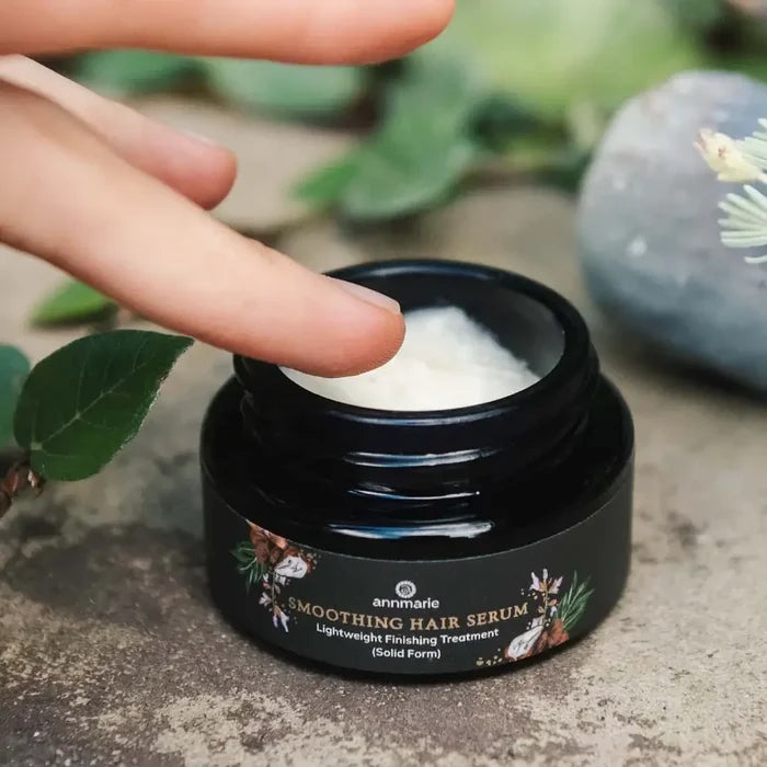 Hand holding a jar of Smoothing Hair Serum with a natural background