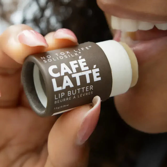 Lip butter stick labeled 'Café Latè' held by a person with blurred background