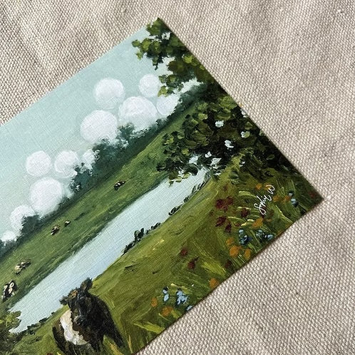 Bring home the charm of the countryside with the SOPHIE WYATT STUDIO - WILD MEADOWS & BELTIES ART PRINT, 11X14. This fine art print by SOPHIE WYATT STUDIO features a scenic green landscape with a pond, trees, colorful flowers, and Belted Galloway cows under puffy white clouds on linen fabric.