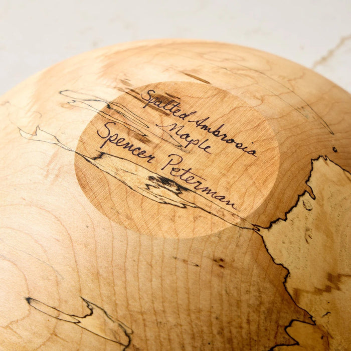 A handcrafted SPENCER PETERMAN - SPALTED MAPLE BOWL 13" by PETERMANS BOARDS & BOWLS INC, featuring a round shape with a light, natural finish and striking spalted maple grain patterns, displayed on a white background.