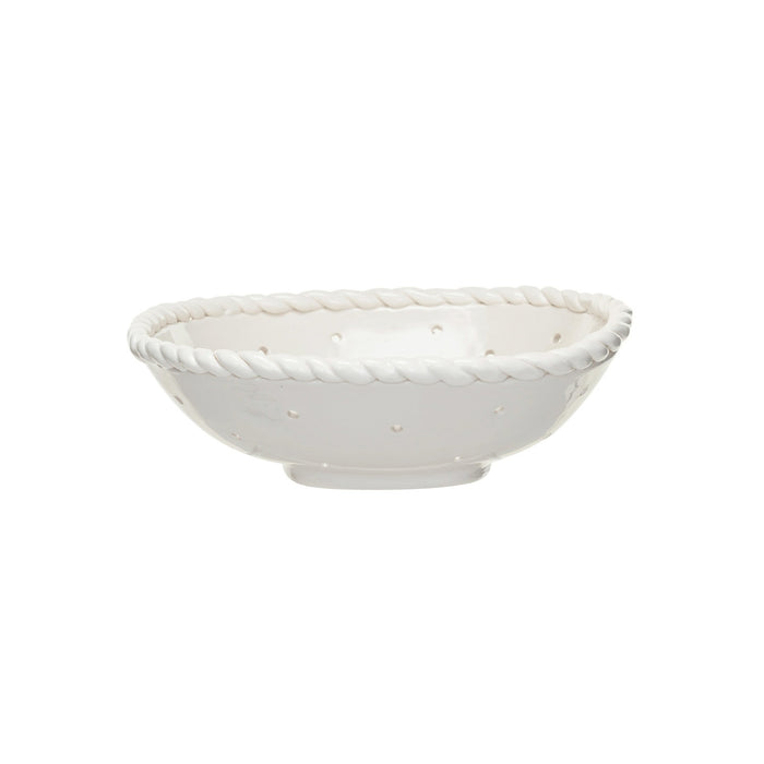 The CREATIVE COOP STONEWARE COLANDER WITH HAND TWISTED EDGE, shown holding three grapefruits on a light textured surface, adds farmhouse charm to any kitchen.
