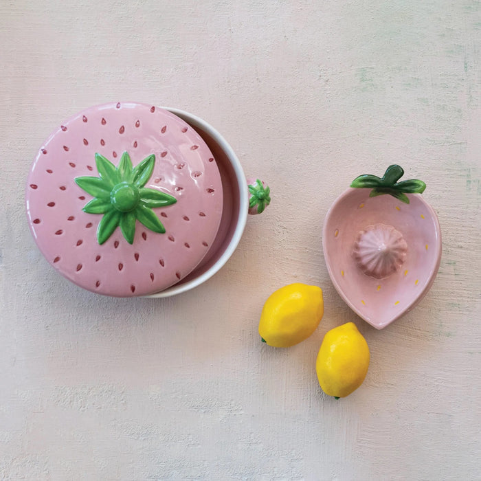 The CREATIVE COOP Stoneware Strawberry Shaped Baker with Handles features a round ceramic design with a lidded top, pink strawberry detail, green leaves, and strawberry-shaped handles—adding rustic charm to any artisan kitchen.