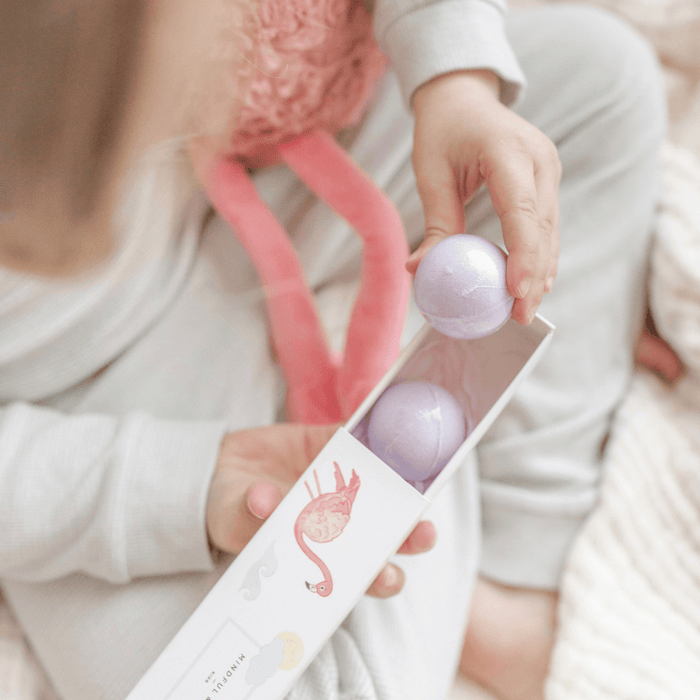 Person holding a box of purple bath bombs with a flamingo design.