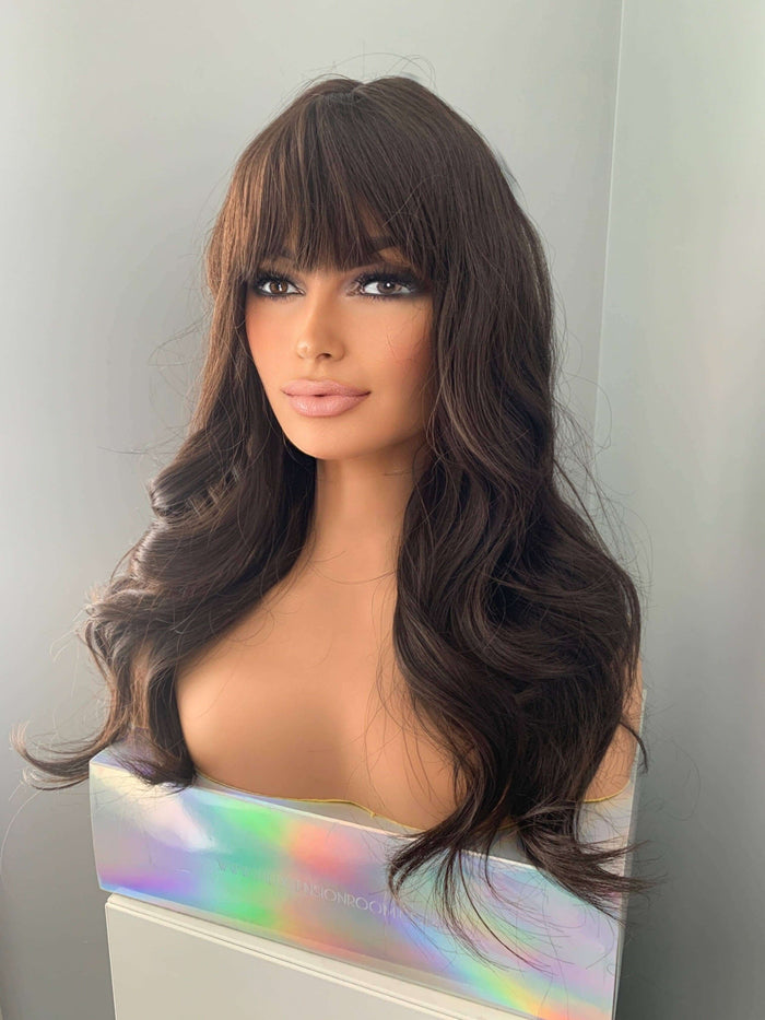 Tasha Long Dark Chocolate Brown Wig with Bangs displayed on a mannequin, featuring soft waves and full fringe.