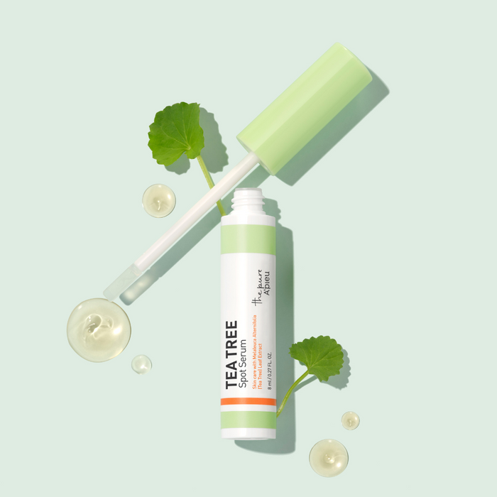 Tea tree spot serum with dropper and leaves on a light green background