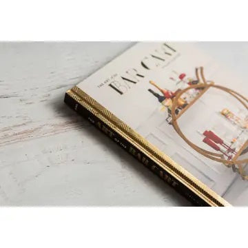 A close-up of THE ART OF THE BAR CART BY VANESSA DINA from CHRONICLE BOOKS, featuring a gold-patterned spine and an illustrated bar cart on the cover—ideal for drink ideas and elegant home bar decor.